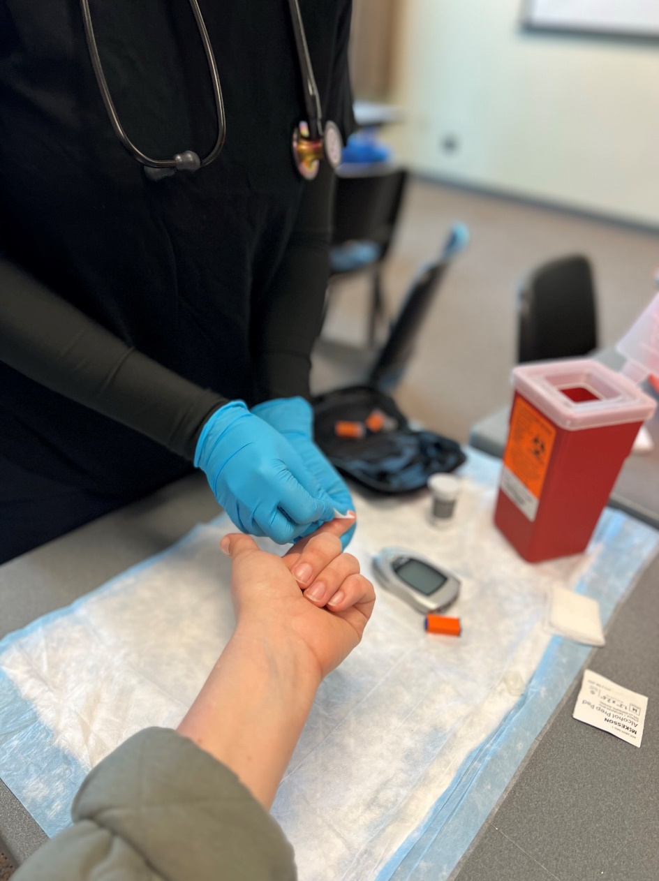 A gloved EMT cleaning a patient's distal end of pointer finger with alcohol prep.