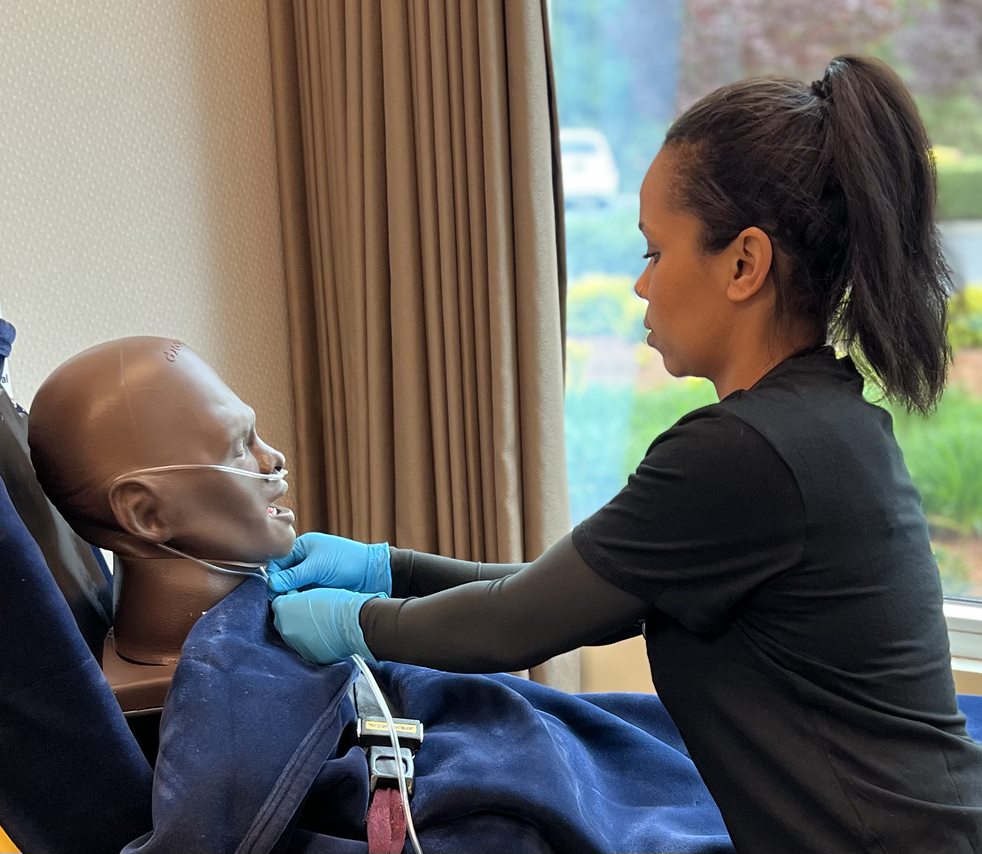 A photo of a gloved EMS clinician gentle securing the nasal cannula around the neck of a simulated patient.