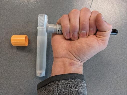 A photo showing proper way to hold an autoinjector to prevent accidental needle stick