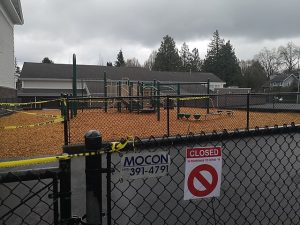 A school building is shut down and yellow tape is placed around the playground to keep people from using it