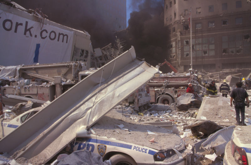 An image of destruction on the streets of New York following the 9/11 Tragedy in which police cars and fire trucks can be seen buried in the rubble.