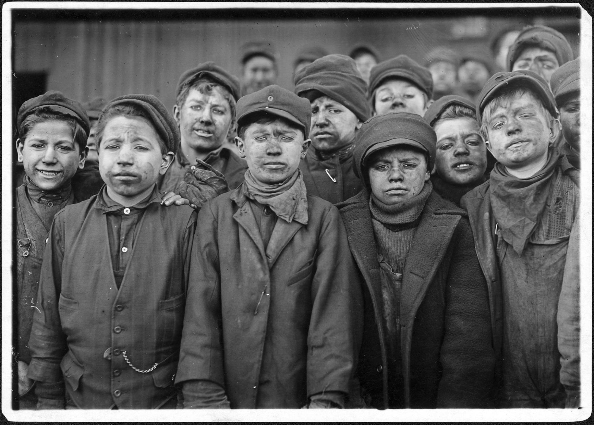 A photo of young boys, who appear to be about 8 to 12 years old, dressed in work clothing with soot on their faces.