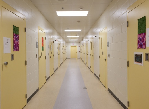A photo of the Department of Youth Services Facility showing the long linear corridor with cells lining either side.
