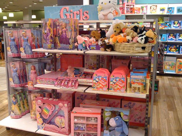 Store display of girls' toys, inluding Disney Princess Barbies and stuffed animals.
