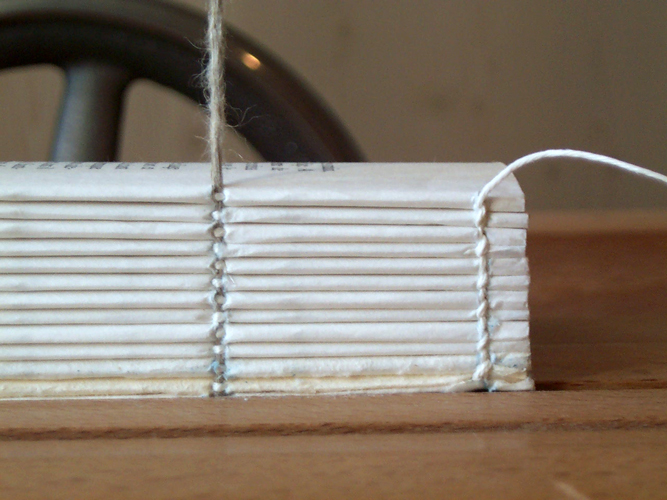 Pages of a book in process of being tied together for binding.
