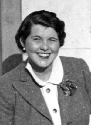 Rosemary Kennedy smiling at the camera. She has short dark hair and wears a white collared shirt and a tweed jacket with a flower at the lapel