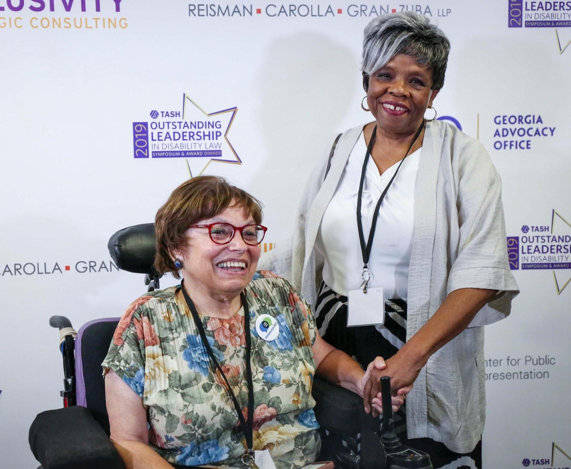 Judith Heumann and Barbara Ransom in front of a backdrop promoting "Outstanding Leadership in Disability Law 2019"