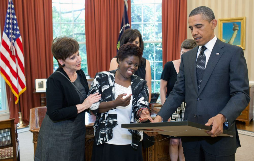 Lois Curtis shows president Obama a painting she made while Obama stands next to her holding the painting.