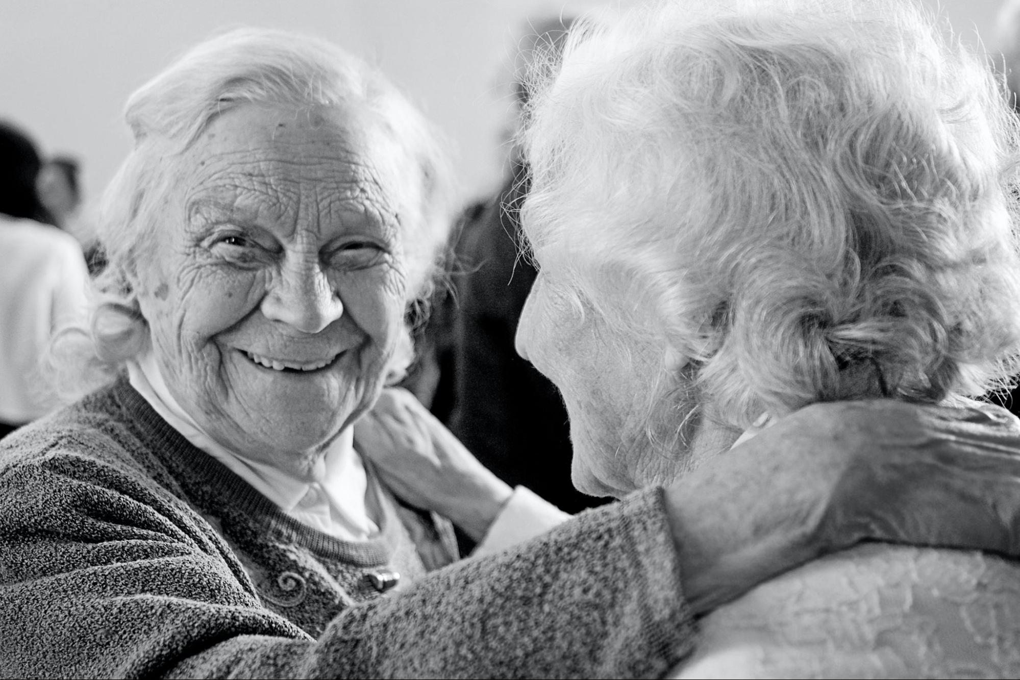 two old White women are smiling and perhaps dancing