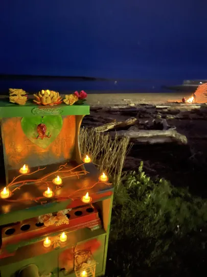 a painted mailbox covered in electric candles on a beach