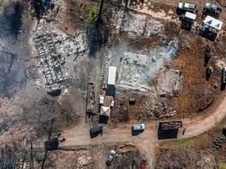 Remains of Echo Mountain Complex Fire structures are burned to the ground. Trees are black and smoke remains.