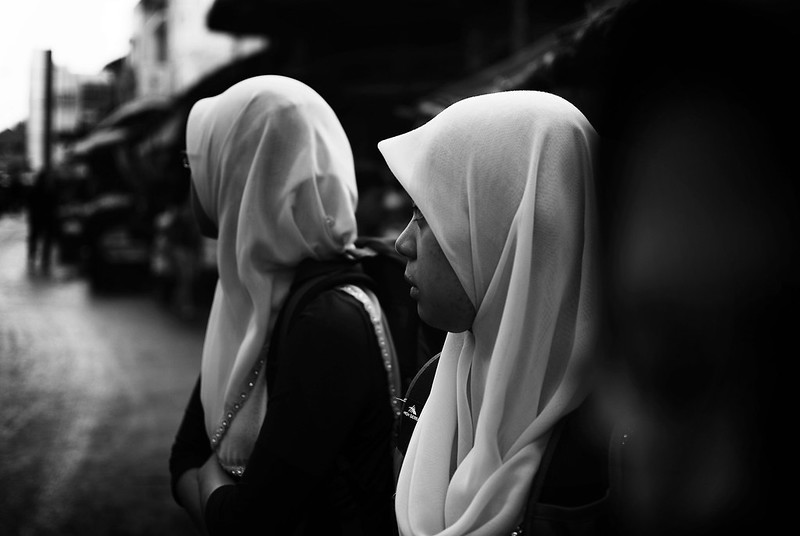 Two women in hijab look down an urban street