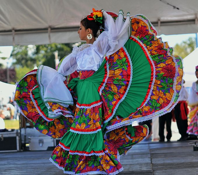 A dancer in a colorful dress sweeps and whirls on stage