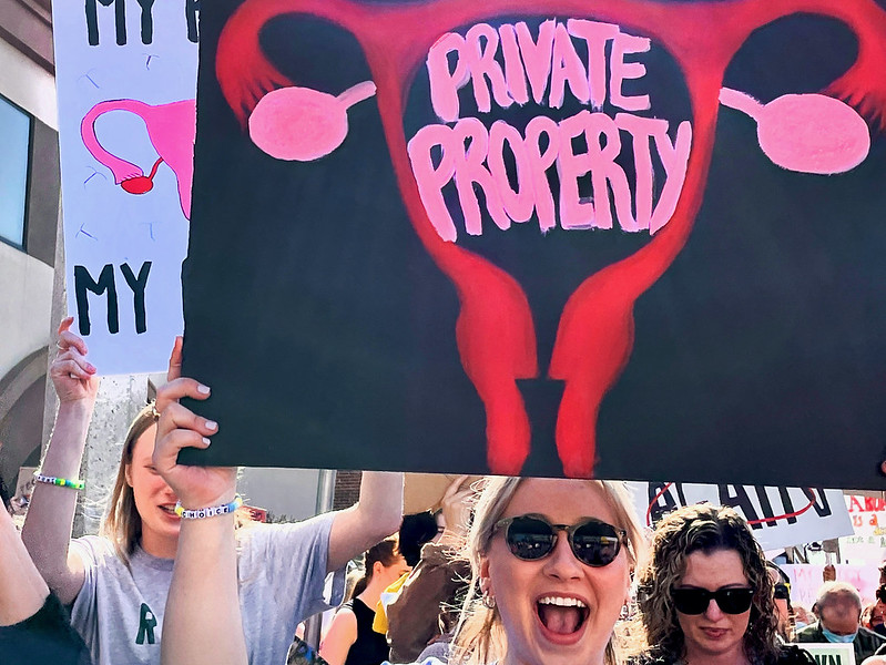 People march and hold signs picturing a uterus with the words 'private property'