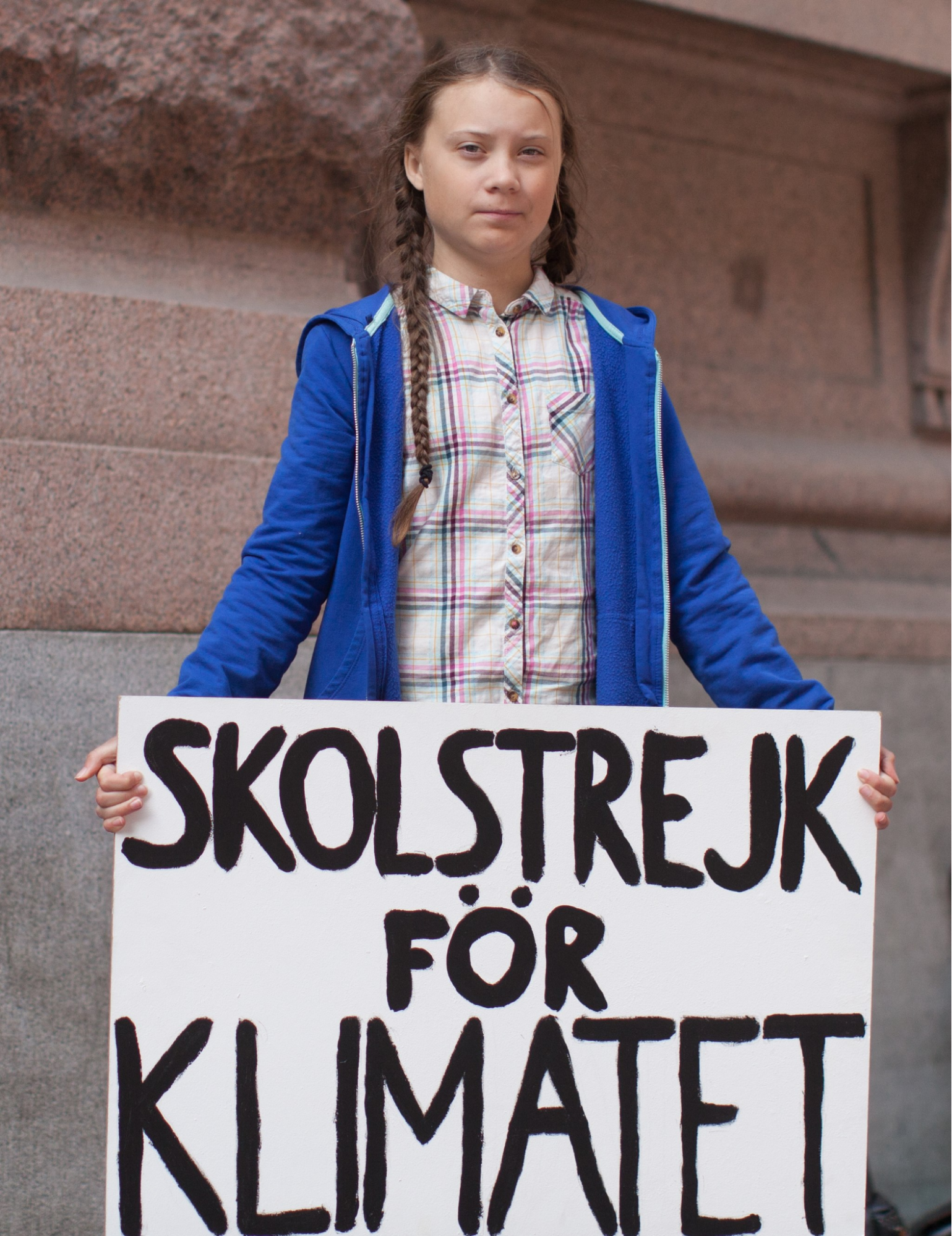 Greta Thunberg holding a sign that says &quot;school climate strike&quot; in Swedish