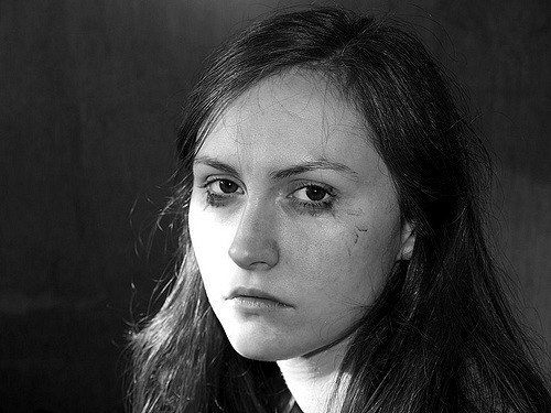 Fig 9.8 A woman looking highly depressed. She is frowning, her hair is messy and her eyes look sad.