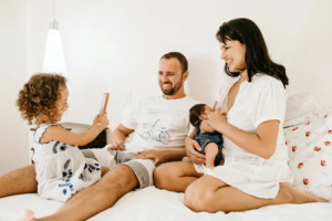 two adults and two children interacting on a bed