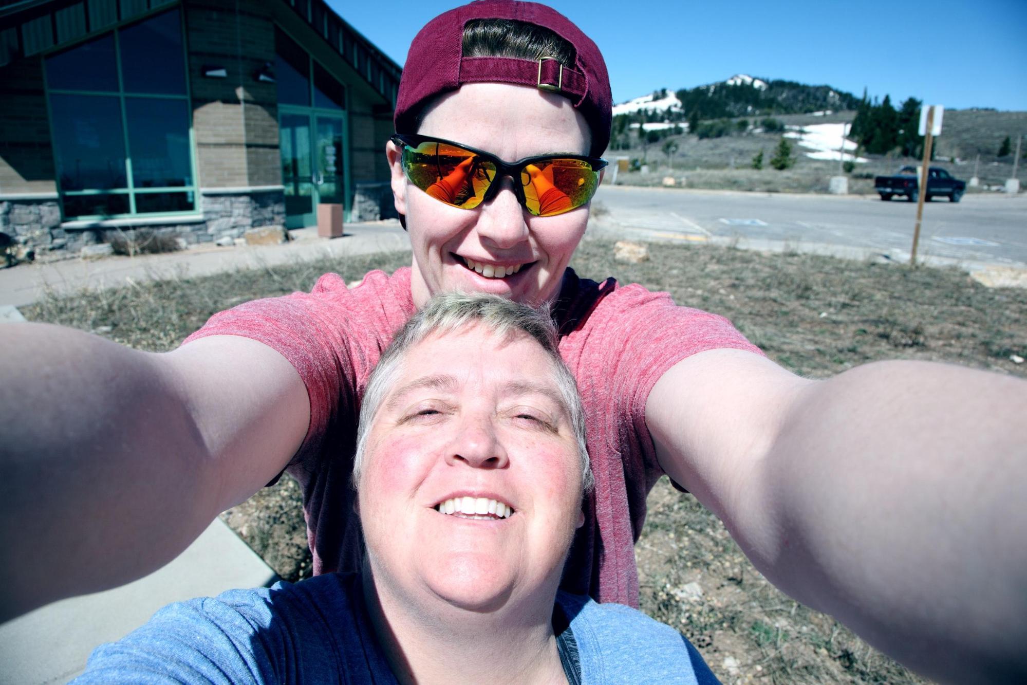 White haired woman with short hair embraced by tall woman with baseball cap