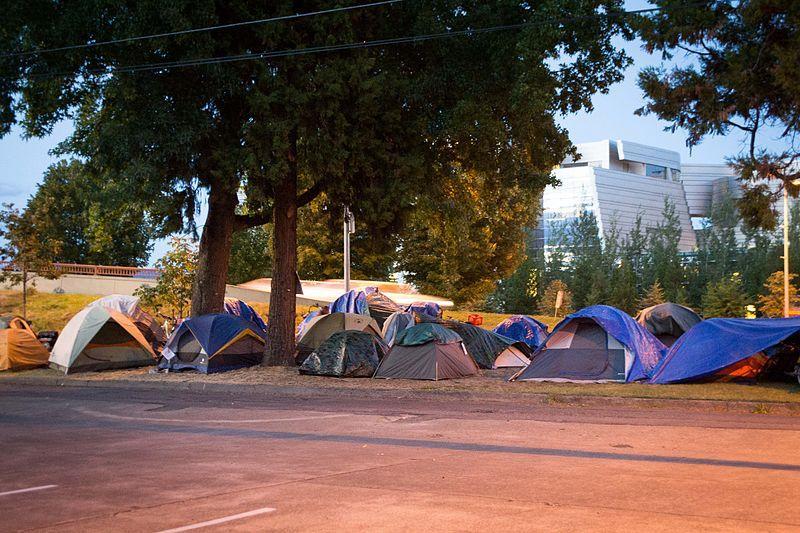 A cluster of tents near a highway.