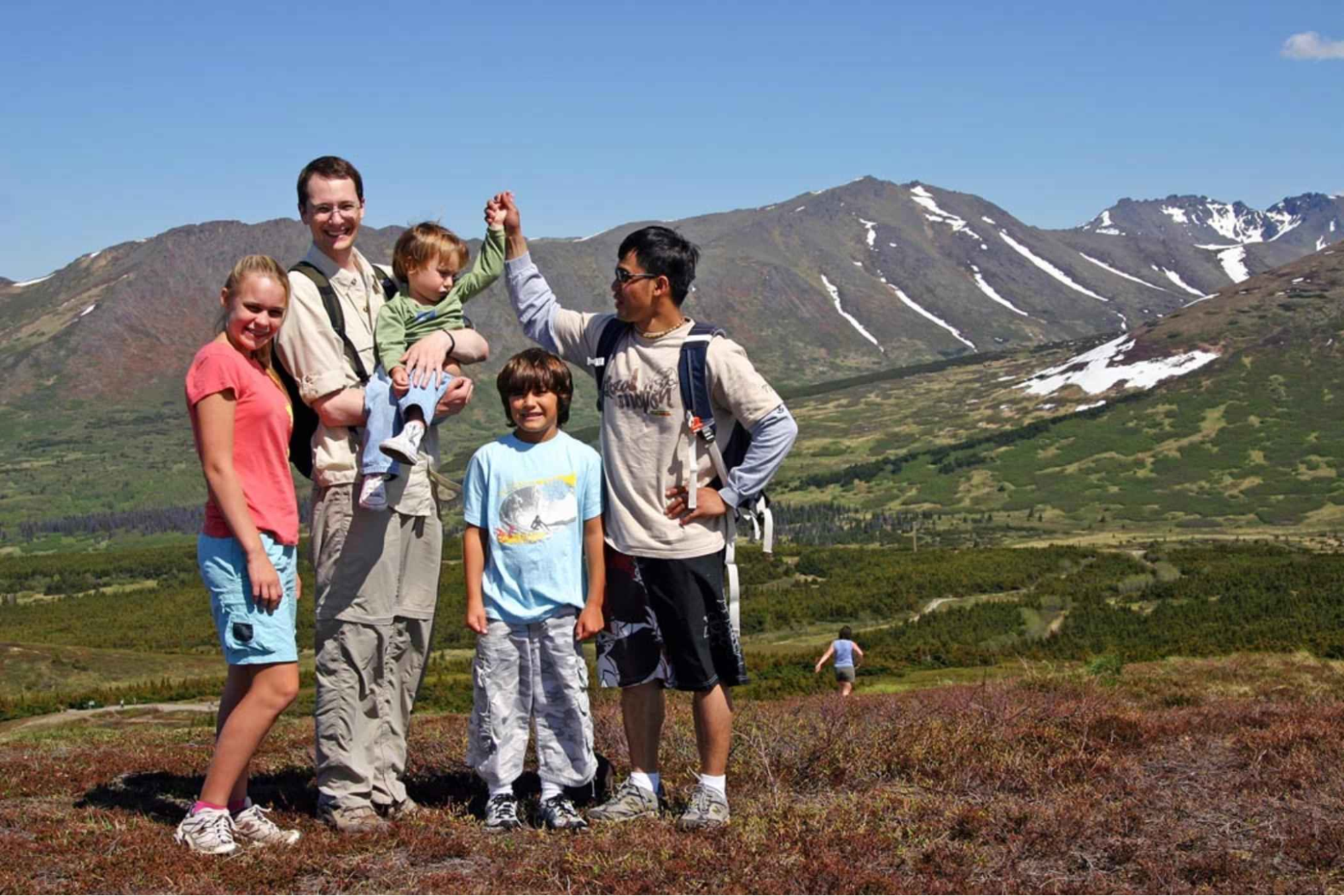 A same-sex couple and their children in a mountain landscape vacation photo.