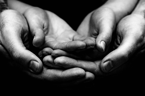 A child’s hands held within their parents hands, face up and open.