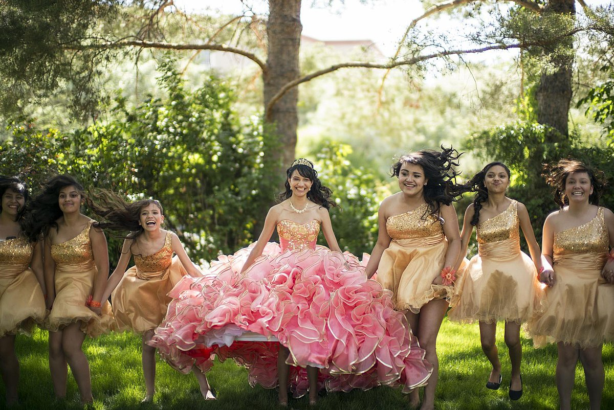 A girl in a quinceanera dress with her friends in the woods.