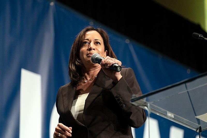 Black woman, Kamala Harris, standing with microphone