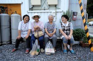 Four Japanese women sitting next to each other, smiling.