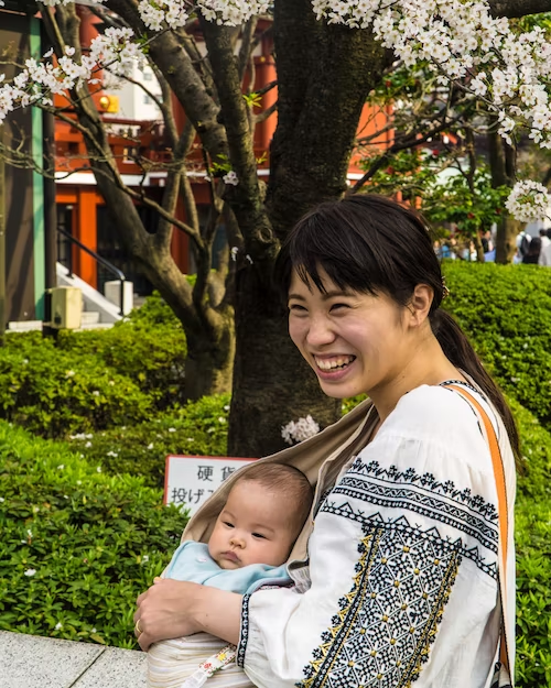 A parent holding their child in a cloth sling.