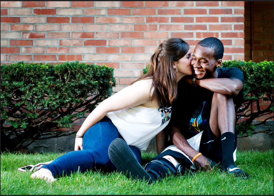 A woman sharing a funny secret with her romantic partner by whispering in his ear.