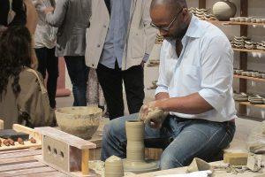 A man making a pot in a pottery classroom.