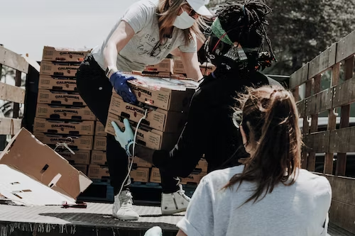 People carrying goods out of the back of a truck.