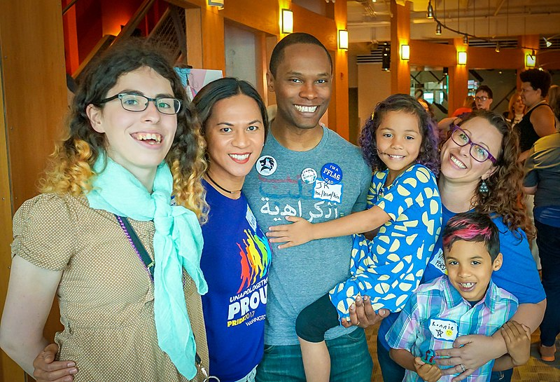 A multigenerational group of people embracing and smiling at an event for Parents and Family of Lesbians and Gays.