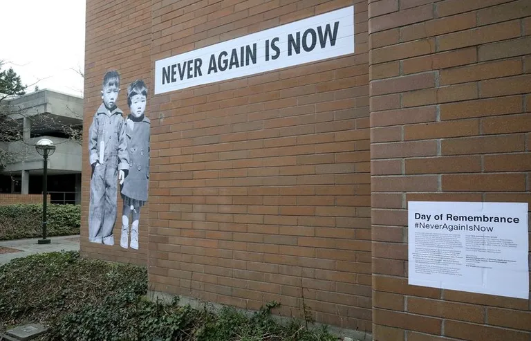 A mural of two incarcerated children and a large statement reading “Never Again Is Now”