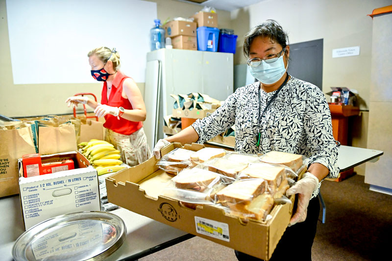 Two workers sorting and moving food at a food pantry.