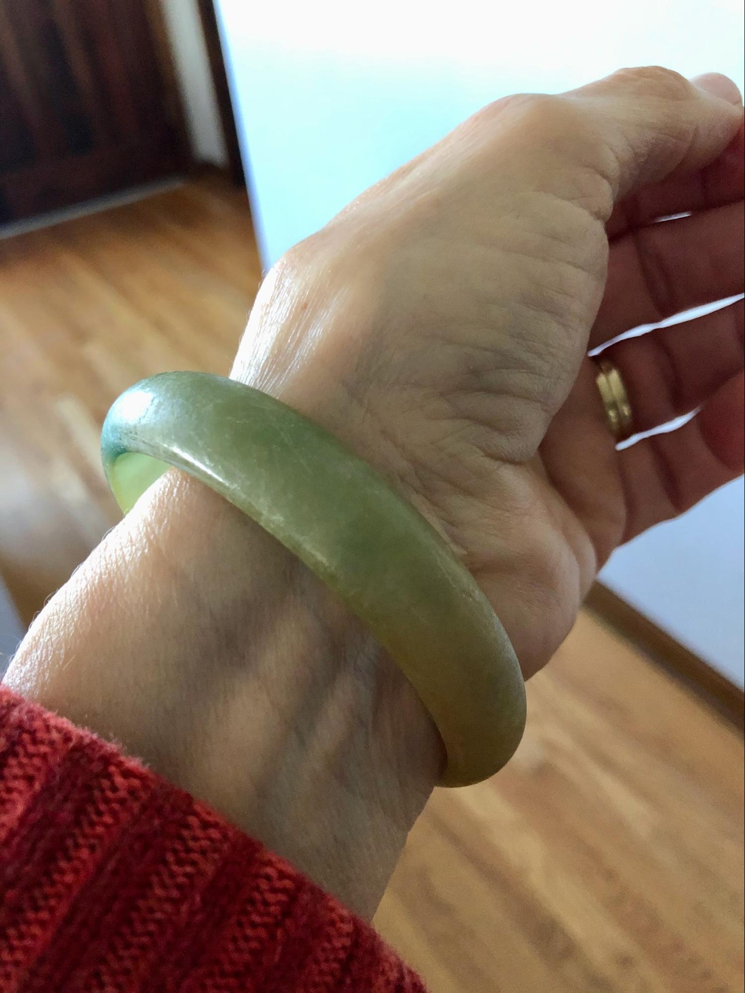 A jade bracelet on a person’s wrist.