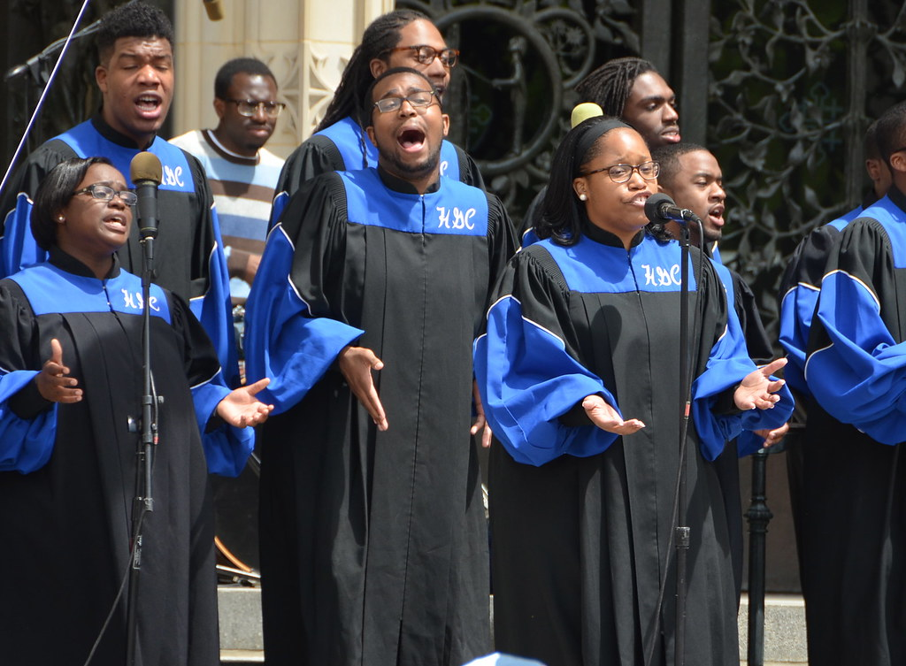 A Black choir sings on public steps.