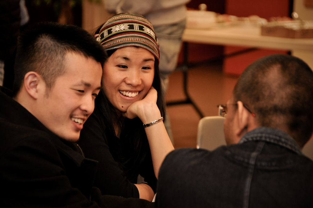 Three people talking at a social gathering with food.