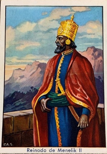 The image is an illustration of King Menelik II after victory over Italy in 1896. Menelik is dressed in rich, colorful garments set against a backdrop of mountains under a blue sky. The figure is shown in profile, facing left, wearing a golden crown with ornate detailing and a yellow robe with intricate patterns over a blue garment. A deep red cloak with golden trim drapes from his shoulders. The setting includes a stone wall, suggesting a terrace or a fortification. The landscape behind displays rugged mountains with hints of greenery, and a sky filled with fluffy clouds in soft pastel hues.