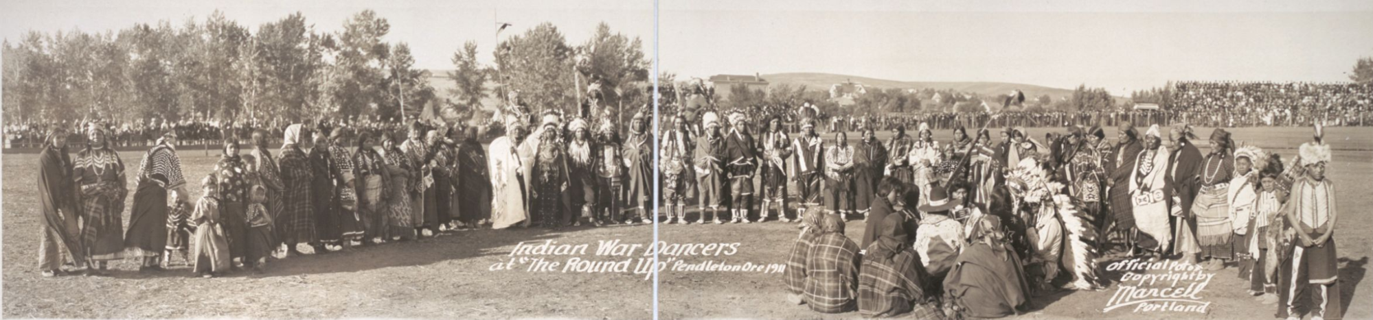 Dozens of tribal members standing in groups and a line as they prepare for a performance. Groups are outside and dressed in regalia.