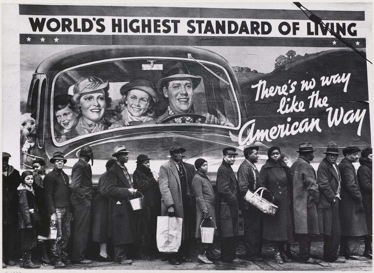 Queue of Black residents of Louisville, Kentucky, waiting for distribution of relief supplies during the 1937 Ohio River flood. Behind them is a mural of a White family driving a car and the phrases "world's highest standard of living" and "there's no way like the American way."