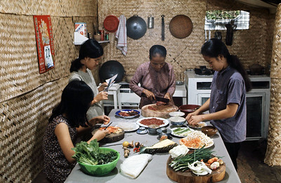 four women of different generations work together a table on various stages of cooking a meal