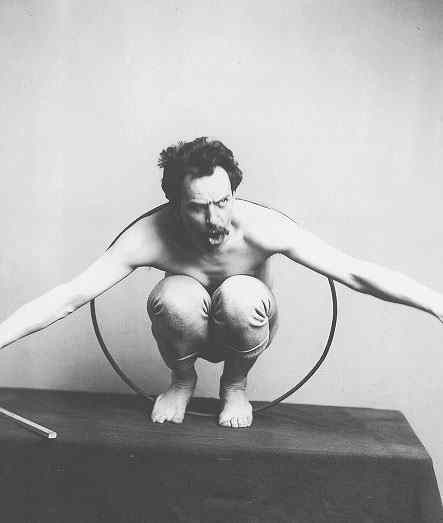 An image of Frank Boas crouching inside of a hoop on a platform.