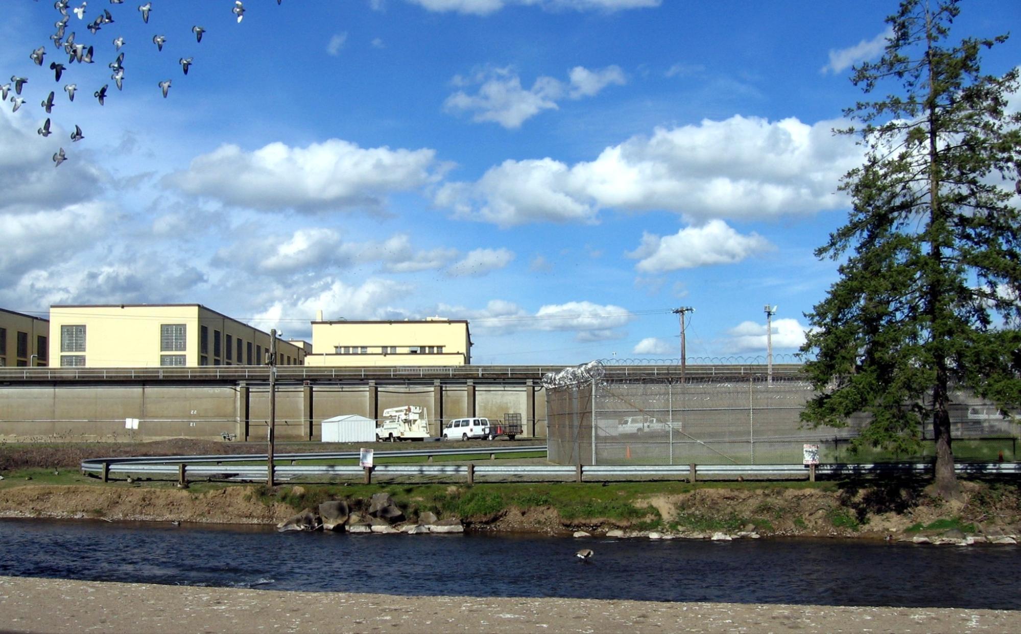 Oregon State Penitentiary. A series of white buildings behind large barbed wire fences.