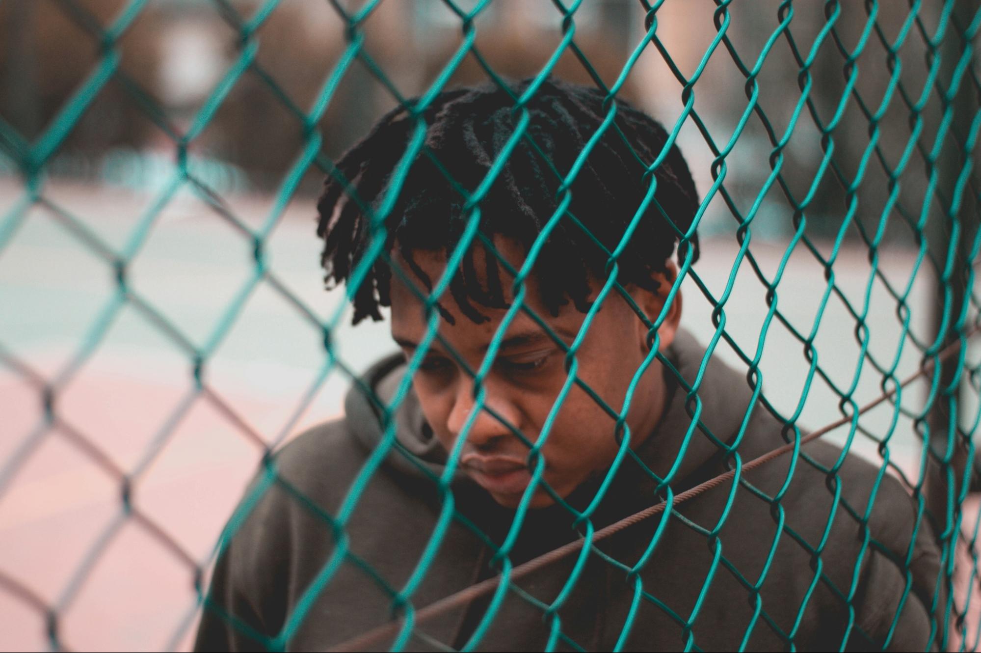 a person looking solemn behind a fence