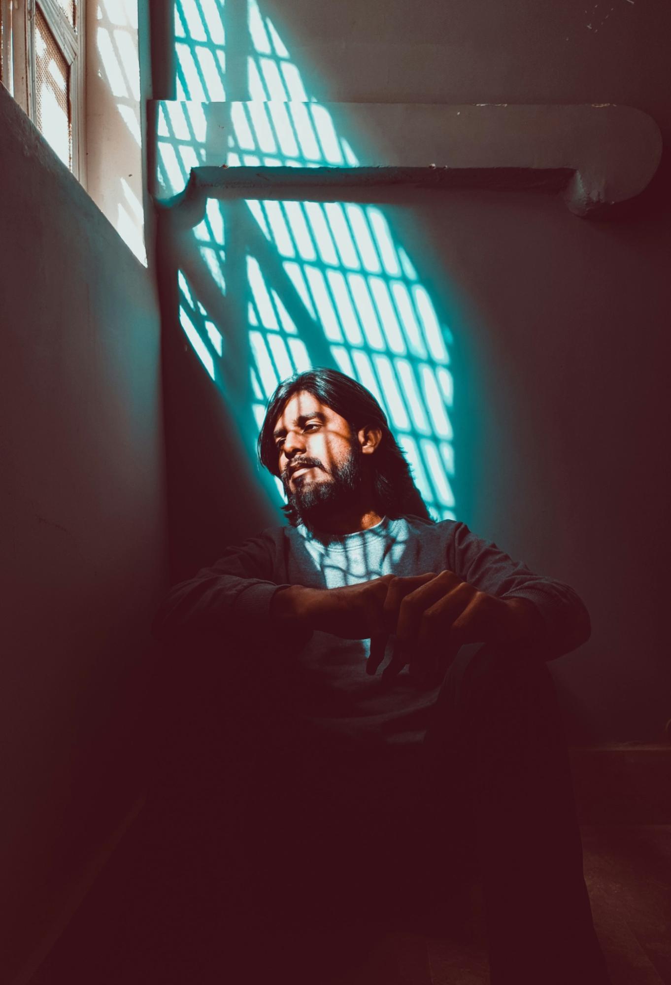 Photo of a person with shadow from a barred window cast over them