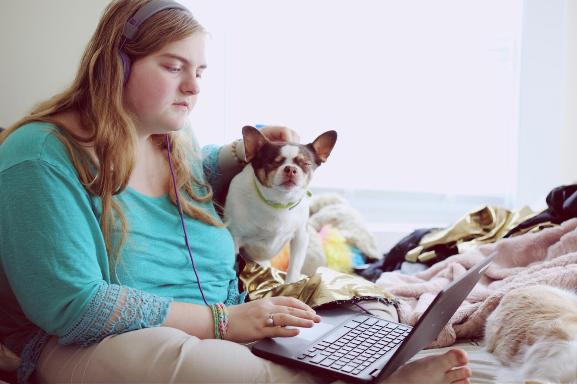 Photo of a person using a laptop and wearing headphones.