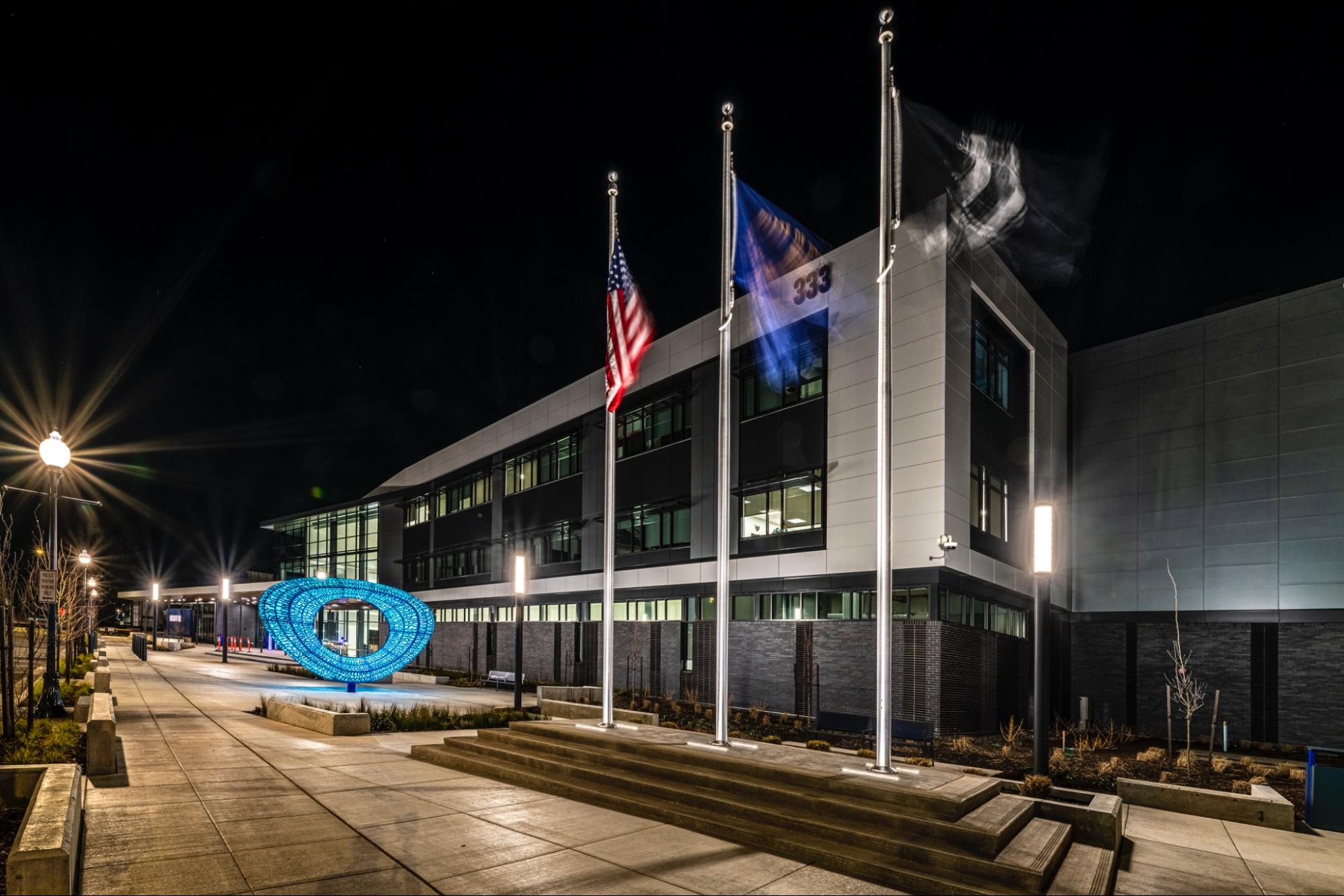 Photo of a public building with a large plaza and three flags in front