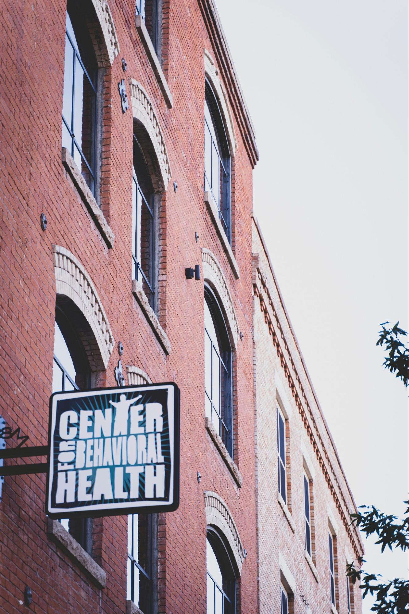 Red brick building with a black sign that says "center for behavioral health"