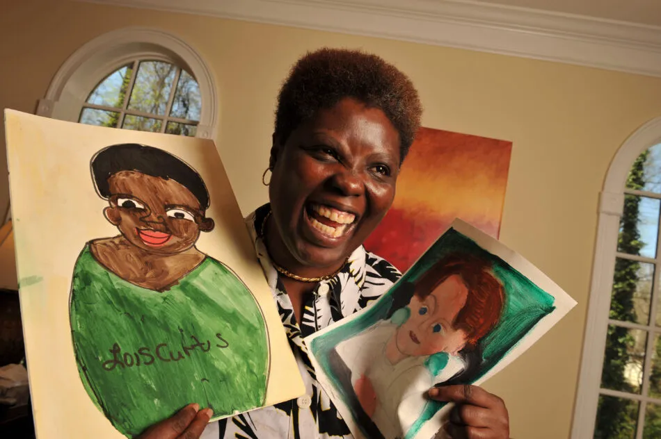 Photo of Lois Curtis holding two drawings.